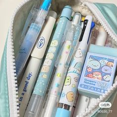 an open pencil case filled with pens and other items in it's zippered pouch