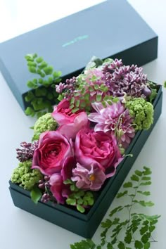 flowers in a box with greenery on the table next to it and an instagram page