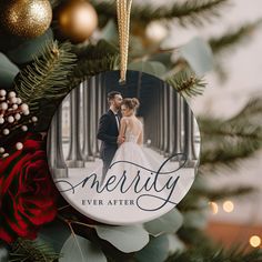 a personalized ornament hanging from a christmas tree with red flowers and greenery