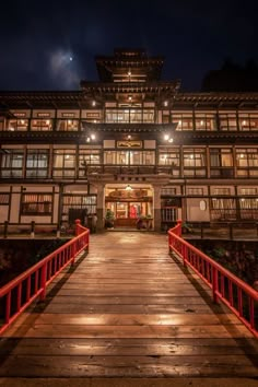 a large building lit up at night with lights on the windows and red railings