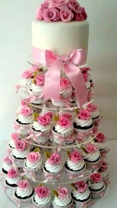 a tiered cake with cupcakes and pink flowers on it