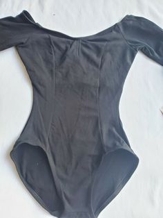 an unbuttoned bodysuit laying on top of a white sheet covered bed