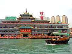 a large boat floating on top of a river next to a tall building