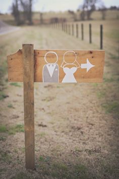 a wooden sign with paper cutouts on it in the middle of a dirt road