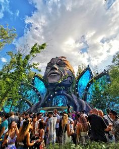 a group of people standing in front of a giant blue creature statue at an amusement park