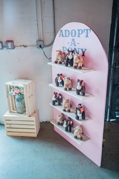 there are many small teddy bears on the shelves in front of this sign that says adopt a pony