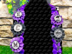 a purple and black ribbon with some badges on it in front of a stone wall