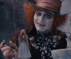 a man dressed as the mad hatter holding a teddy bear in his right hand