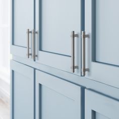 a close up view of the handles on some blue cupboards with white walls and wood flooring