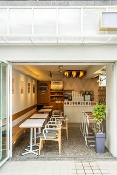 the inside of a coffee shop with tables and chairs in front of an open door