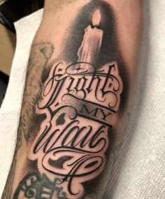 a man's arm with a candle and lettering on it