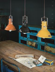 an old wooden table with three hanging lights above it and other items on the table