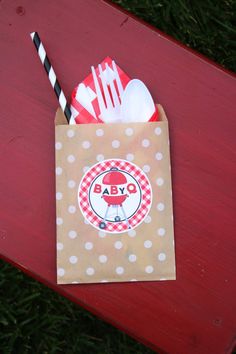 a brown paper bag sitting on top of a red table next to a fork and spoon