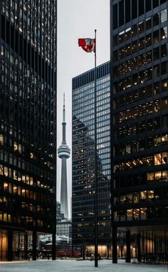 the canadian flag is flying high in the sky above some tall buildings and skyscrapers