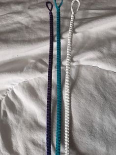 two necklaces laying on top of a bed next to each other, one blue and the other white