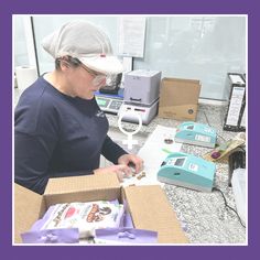 a woman in a white hat and glasses working on some type of machine with boxes around her