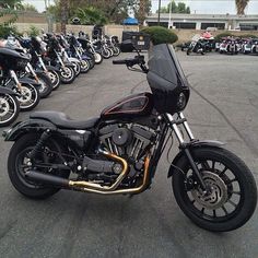 a black motorcycle parked in a parking lot next to many other motorcycles on the street