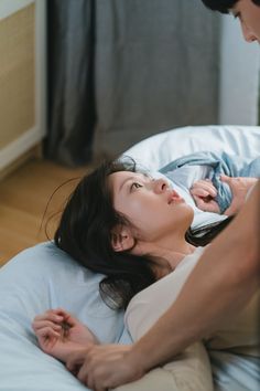 a woman laying on top of a bed next to a man holding a baby in her arms