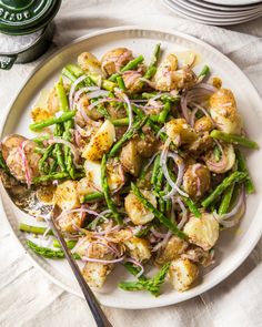 a white plate topped with asparagus and potatoes next to a bottle of beer