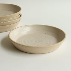 four white bowls are stacked on top of each other, with one bowl in the middle