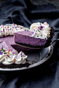 a slice of purple cake with sprinkles on it and a fork in the foreground