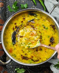 a spoon in a large pot filled with soup and garnished with parsley