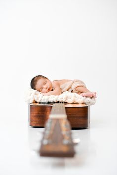 a baby sleeping on top of a wooden box with a guitar in front of it