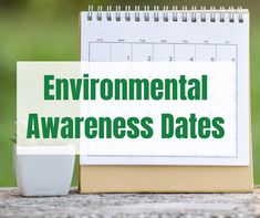 a calendar with the words environmental awareness dates next to a cup of coffee on a table