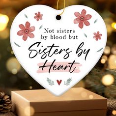 a white heart shaped ornament that says, not sisters by blood but sisters by heart