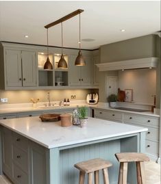 a kitchen island with two stools in front of it and three lights hanging from the ceiling