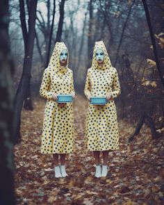 two women dressed in yellow and blue are standing in the woods with their faces painted like polka dots