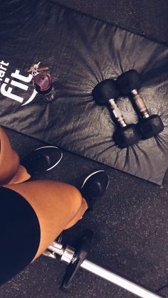 a woman standing next to a pair of dumbbells on top of a gym floor