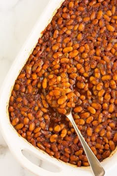 baked beans in a white casserole dish with a spoon