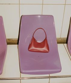 three pink and purple chairs sitting next to each other on a tile floor in a bathroom