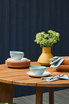 a wooden table topped with plates and bowls