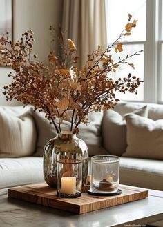 a glass vase filled with flowers sitting on top of a table next to a candle