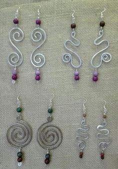 several different types of earrings hanging on a piece of cloth with beads attached to them