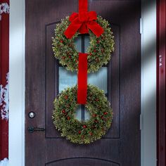 two wreaths with red bows hang on the front door to give an inviting welcome