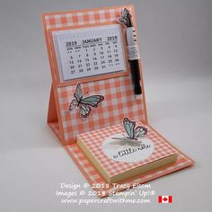 an orange and white checkered desk calendar with a black pen in it's holder