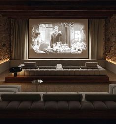 an empty room with couches and a projector screen in the corner, showing a movie scene