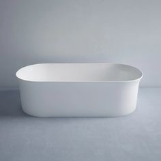 a white bath tub sitting on top of a grey floor next to a gray wall