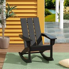 a black rocking chair sitting on top of a wooden floor next to a potted plant