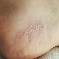 a person with a tattoo on their foot that reads,'faith'in white ink