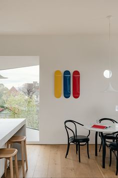 a dining room table with four chairs in front of it and three surfboards on the wall