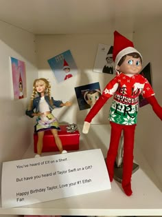 two elf dolls sitting on top of a shelf next to a sign that says happy birthday taylor