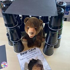 a stuffed bear is sitting in front of stacks of beer cans and a sign that says bear cave