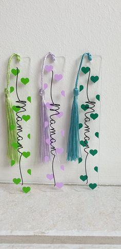 three tasseled bookmarks hanging on a wall with hearts and the word mama