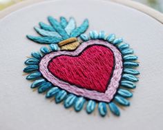 a close up of a heart on a piece of cloth with blue and pink thread