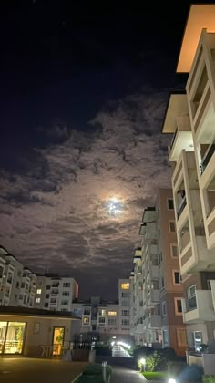 the night sky is lit up with clouds and stars above apartment buildings in an urban area