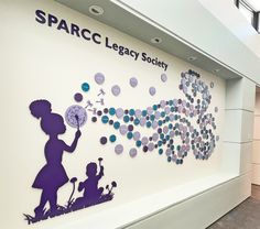 This whimsical, colorful recognition wall has donor names printed on acrylic circles with sprayed colors on the backs. The boy and girl silhouettes are also fabricated from acrylic. Painted aluminum letters title the wall. The overall size is approximately 65” x 125”. Institute Wall Design, Donor Recognition Wall Ideas, Donor Wall Design Ideas, Donor Wall Design, Gala Decorations